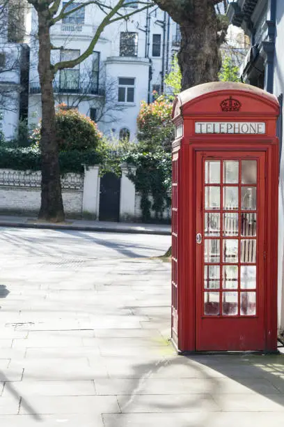 Photo of London - March 30: Iconic red phone booth in front of white town houses in Kensington on March 30, 2017.