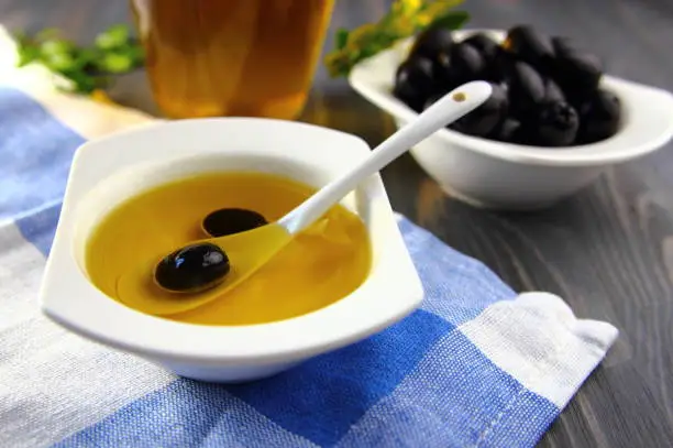 olive in a white ceramic spoon with olive oil