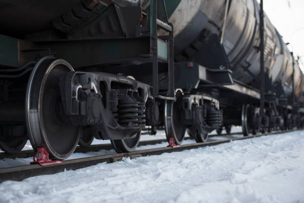 Railway oil tank wagon car carriage at station in winter. Focus on rail wheels blocked by red stoppers.