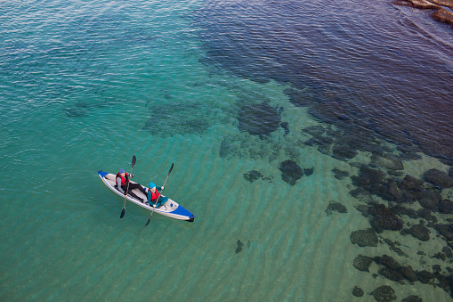 High angle view of mature couple kayaking in Mediterranean sea, Shavei Zion beach. The sea water is clear and sea bottom is visible.