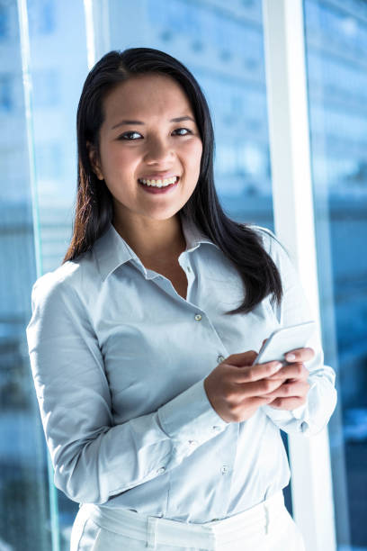 istock Smiling businesswoman using smartphone and looking at camera 666608320