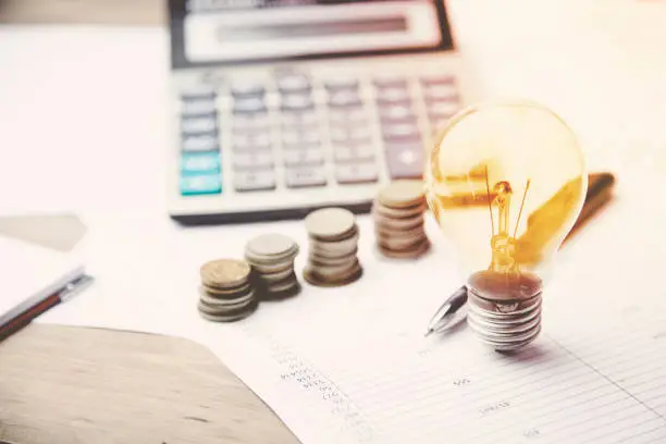 money,calculator and light bulb   on the financial papers