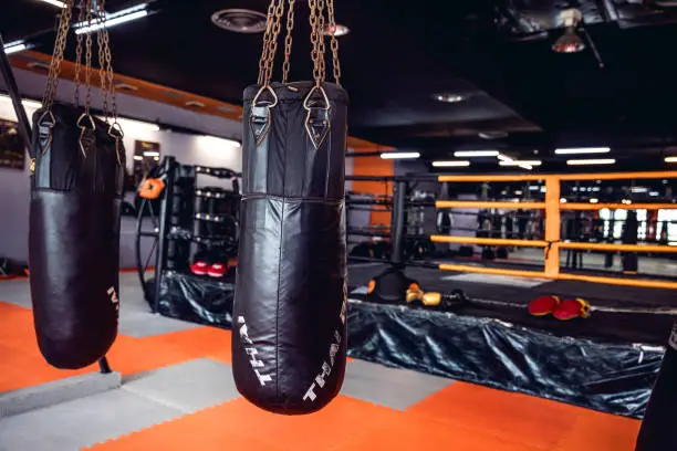 Modern thai boxing gym in Thailand, boxing ring and punching bags visible in the image.
