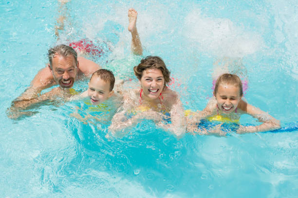 istock Happy parents and kids having fun in pool 666623982