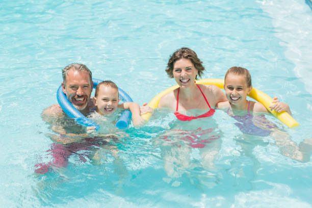 istock Happy parents and kids having fun in pool 666624170