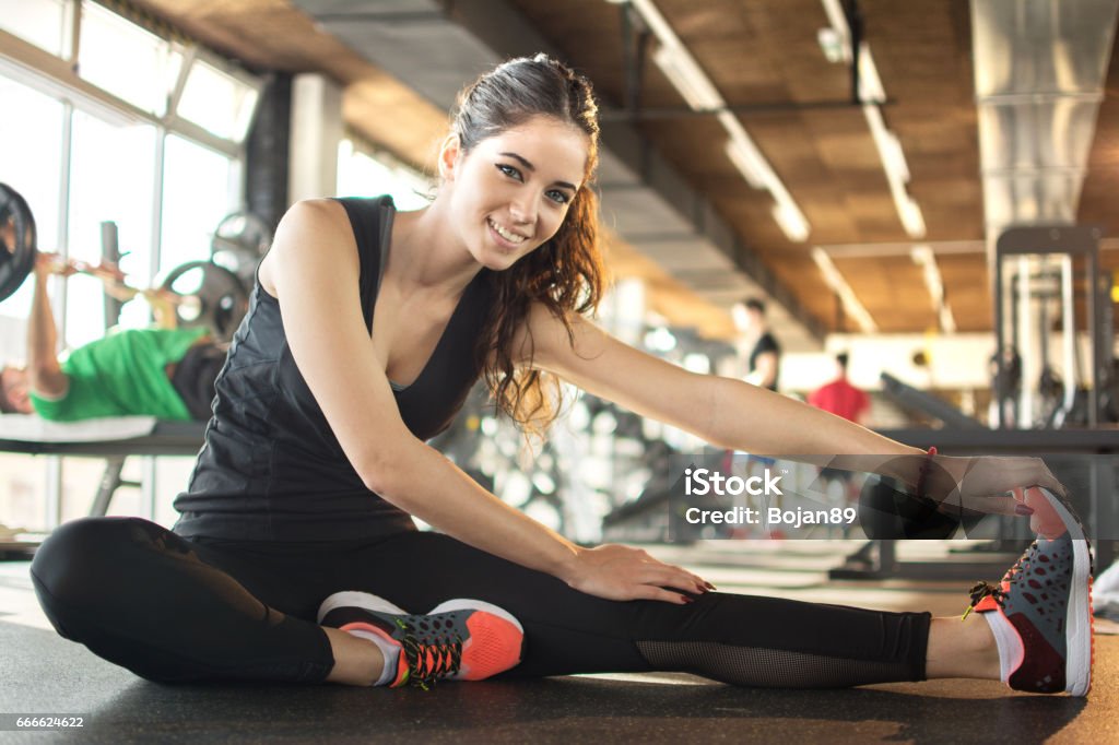 Lächelnde sportliche Frau stretching am Gym. - Lizenzfrei Dehnen Stock-Foto