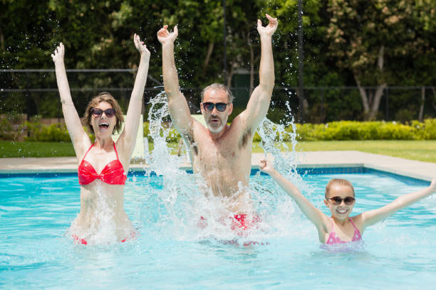 istock Happy parents and daughter having fun in pool 666625126