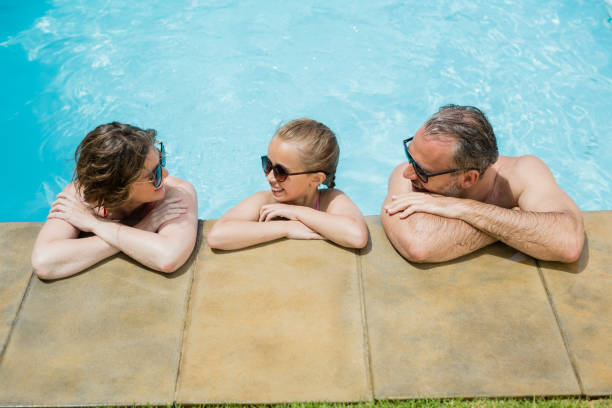 istock Happy parents and daughter relaxing in pool 666627526