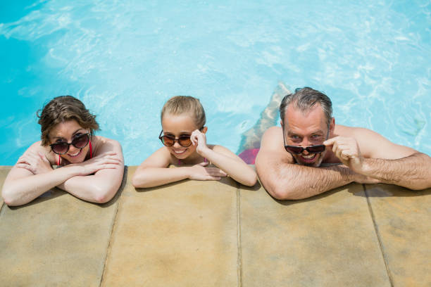 istock Happy parents and daughter relaxing in pool 666627590