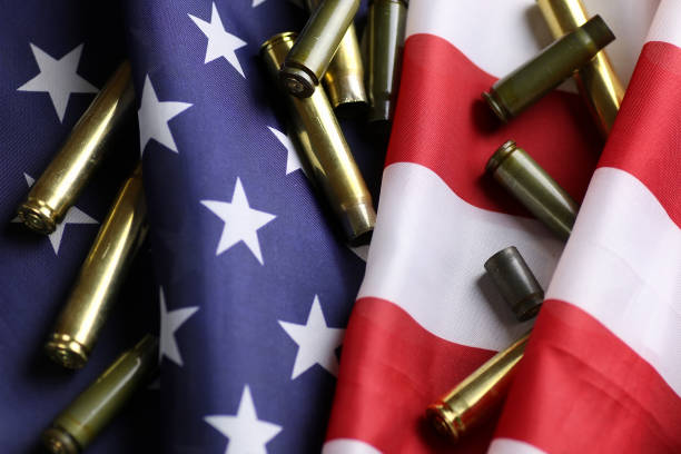 bullet on the USA flag many shell casings from bullets of different caliber in the background chaos concept in the world weaponry stock pictures, royalty-free photos & images