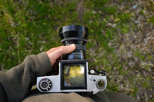 man photographer is making landscape photography with old film camera in spring or summer, tourism and hiking concept.