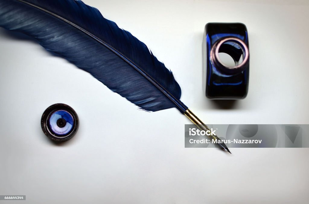 Ink and quill Opened bottle of blue ink and quill over white paper Quill Pen Stock Photo