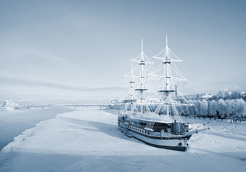 Ship schooner on the shore of the frozen lake of the river