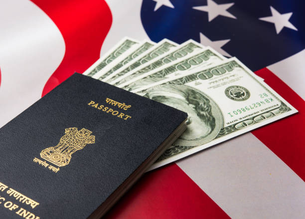 istock concept showing Indian passport with US currency notes or Dollars with american flag in the background, applying for US / american tourist or H-1B visa or travel visa 666661776