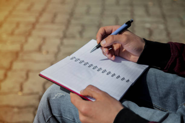 istock Man's hand writing on notebook, sketchbook outdoors 666692054