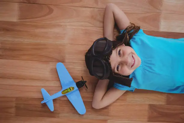 Photo of Smiling girl laying on the floor wearing aviator glasses and hat