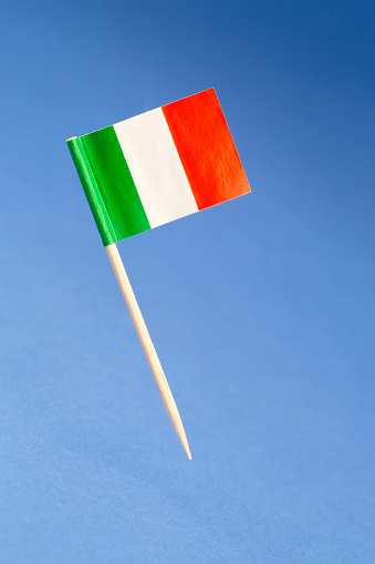 Paper flag of Italy on blue background