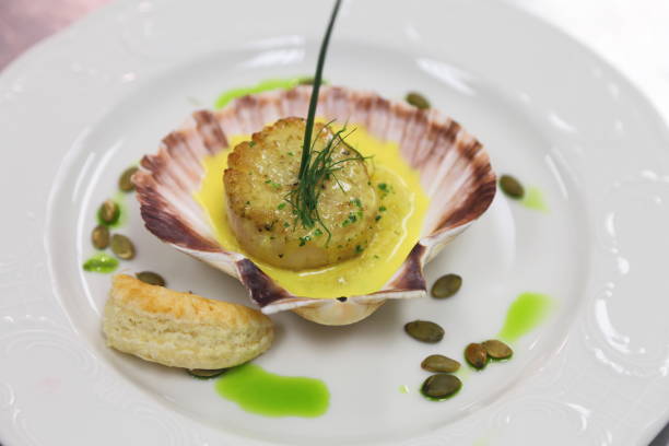 istock Scallop in a shell with grits, pumpkin seeds and saffron sauce. 666710330