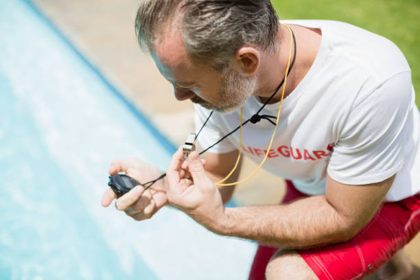 istock Swim coach looking at stop watch near poolside 666738312