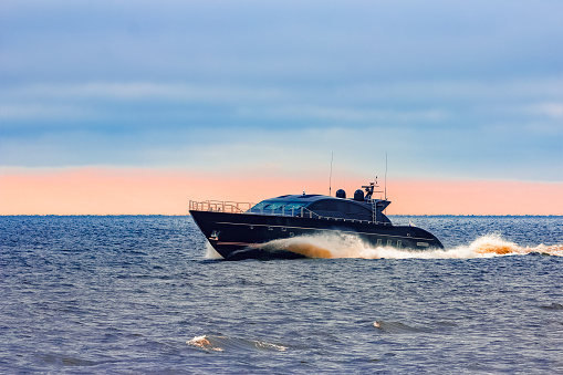 Black elite speed motor boat moving fast from Baltic sea