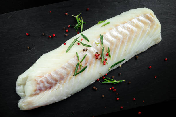 istock Fresh Raw Cod loin fillet with rosemary, cracked pepper on stone board 666744058