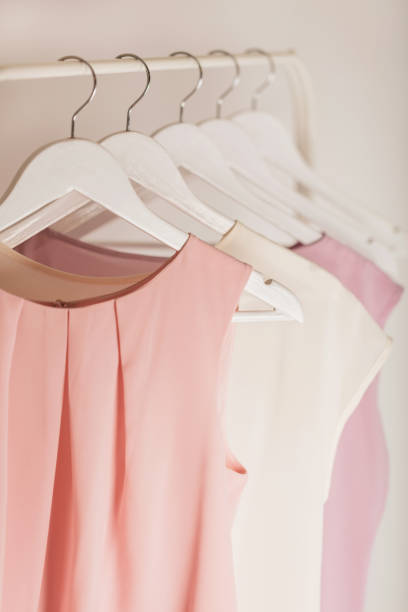 abbigliamento donna in toni rosa su un appendiabiti bianco. - arch top foto e immagini stock