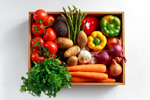 Fresh Vegetables in wooden box on white wooden background.