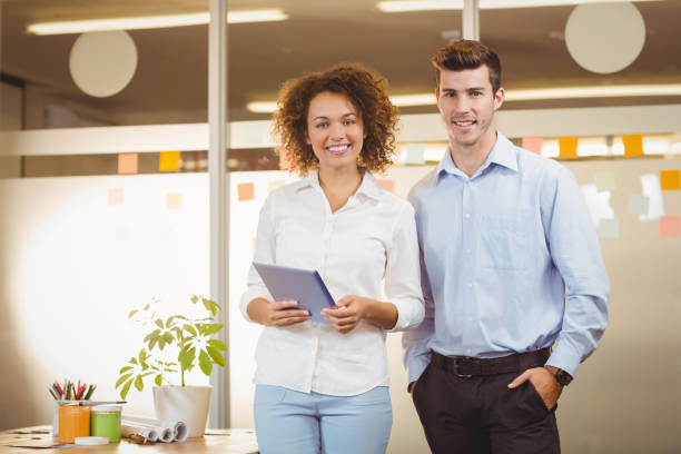 istock Portrait business woman using digital tablet while male colleague 666756546