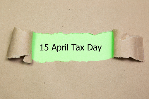 The word 15 april tax day appearing behind torn paper.