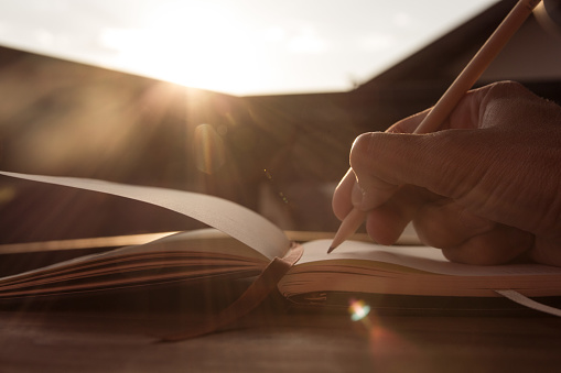 Hand writing in note pad in the sun