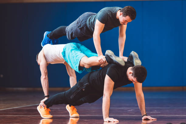 трое молодых людей делают упражнения баланса в тренажерном зале - yoga challenge for 3 стоковые фото и изображения
