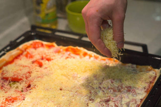 Cook sprinkling shredded cheese over pizza background
