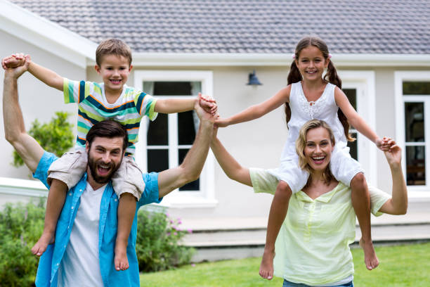 istock Happy parents carrying children on shoulder at yard 666779246