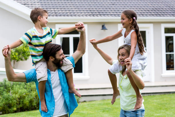 istock Parents carrying children on shoulder in yard 666779440