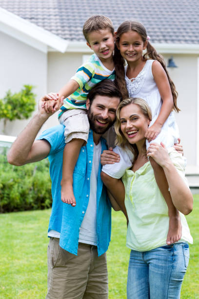istock Happy parents with children on shoulder at yard 666779630