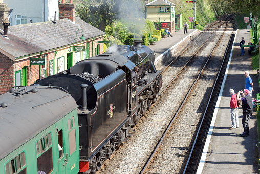 Medstead, UK. 8th April 2017. A steam train is pulling in to the platform at Medstead station on the Watercress Heritage railway line on a sunny spring day. Some people are waiting on the platform.