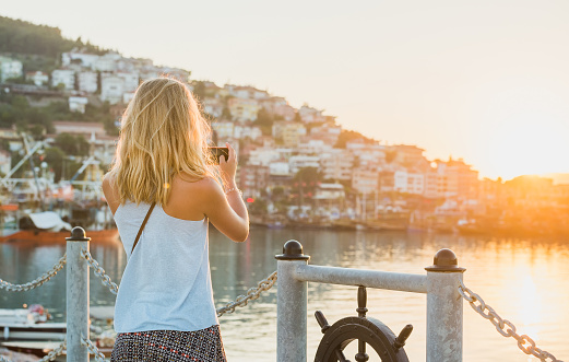 Young blond tourist woman making photo of sunset, Alanya, Turkey