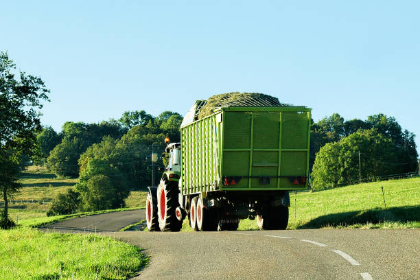 Tractor with trailer full of hay in Bourgogne Franche Comte Tractor with trailer full of hay on the road in Bourgogne-Franche-Comte region in France. doubs photos stock pictures, royalty-free photos & images