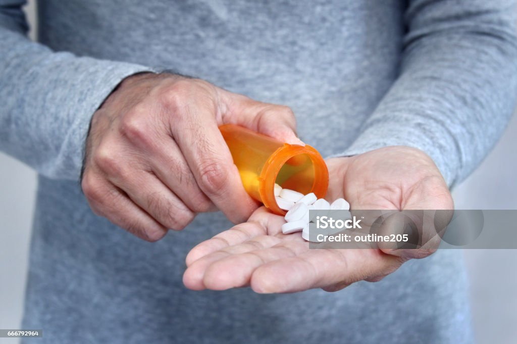 Man taking pills Hands of man holding pill bottle with pills on hand Medicine Stock Photo