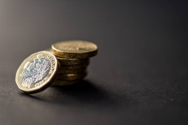 nova moeda britânica de libra esterlina em fundo escuro - coin british currency british coin stack - fotografias e filmes do acervo