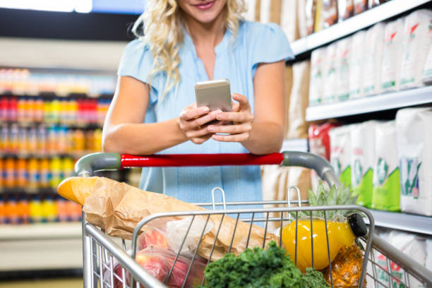 istock Smiling woman with cart using smartphone 666801774
