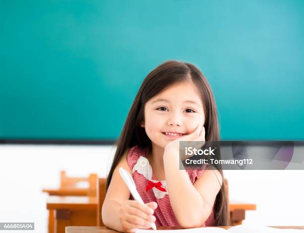 Happy Little Girl Writing At Desk In Classroom Stock Photo - Download Image Now - Child, Elementary Student, Writing - Activity