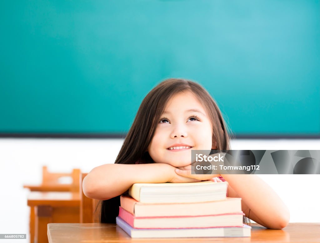 petite fille heureuse avec des livres et la pensée dans la salle de classe - Photo de Enfant libre de droits