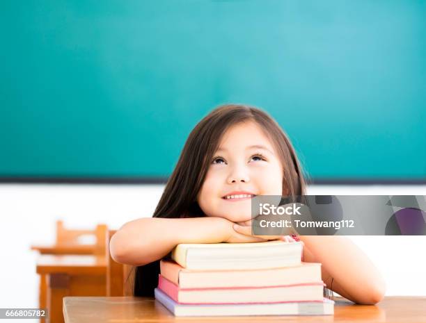 Happy Little Girl With Books And Thinking In Classroom Stock Photo - Download Image Now