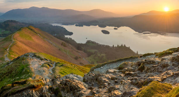 Vibrant Lake District Sunrise On A Calm Spring Morning. Sun rising above horizon at Derwentwater illuminating the landscape with vibrant Spring light. keswick photos stock pictures, royalty-free photos & images