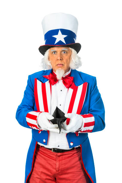 Uncle Sam holding an empty wallet while standing against a white background A patriotic Uncle Sam character holding an empty black wallet. He is wearing a red, white and blue coat and top hat that has a blue ban and white star while standing in from of a white background. uncle sam broke stock pictures, royalty-free photos & images