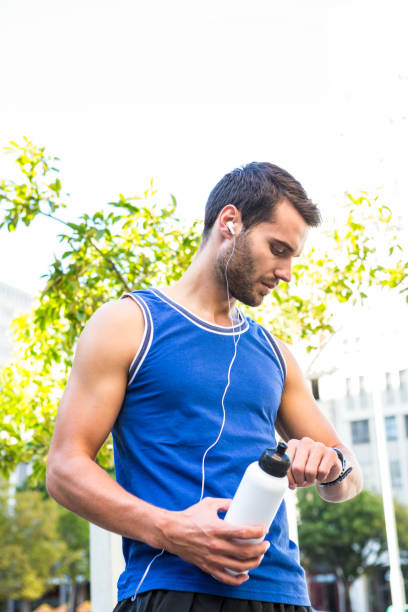 istock Handsome athlete with bottle checking heart rate watch 666814892