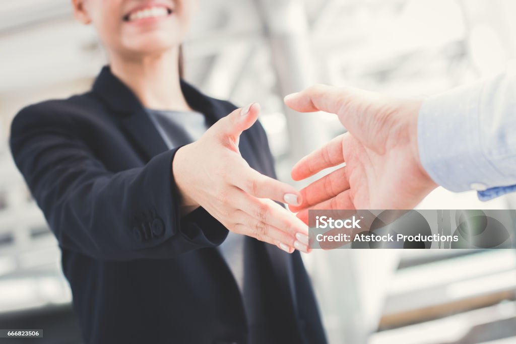 Jovem empresária fará o aperto de mão com um homem de negócios - Foto de stock de Dar as Mãos royalty-free