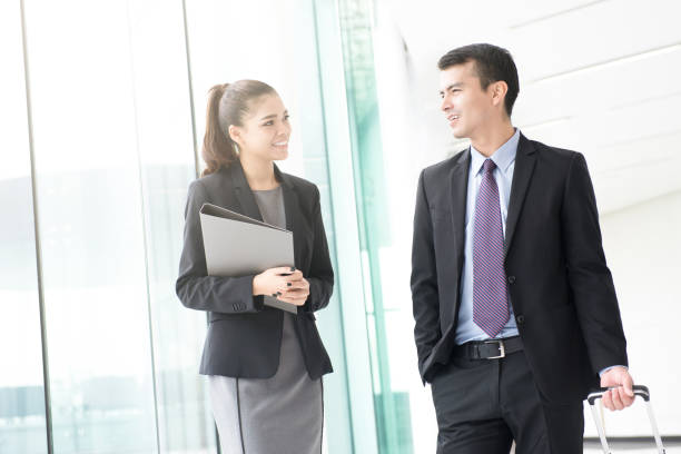 istock Businessman walking and pulling luggage handle while talking with a businesswoman 666823518