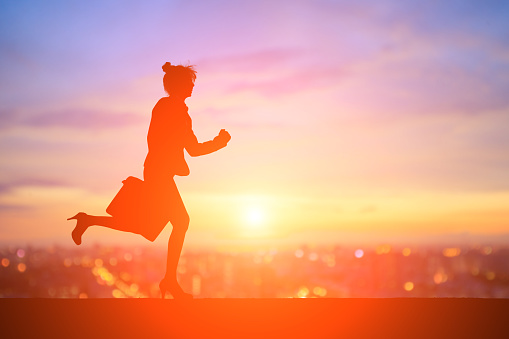 silhouette of business woman running with sunset
